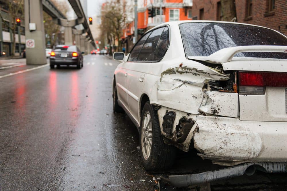A white car’s bumper is caved in after a hit-and-run accident.