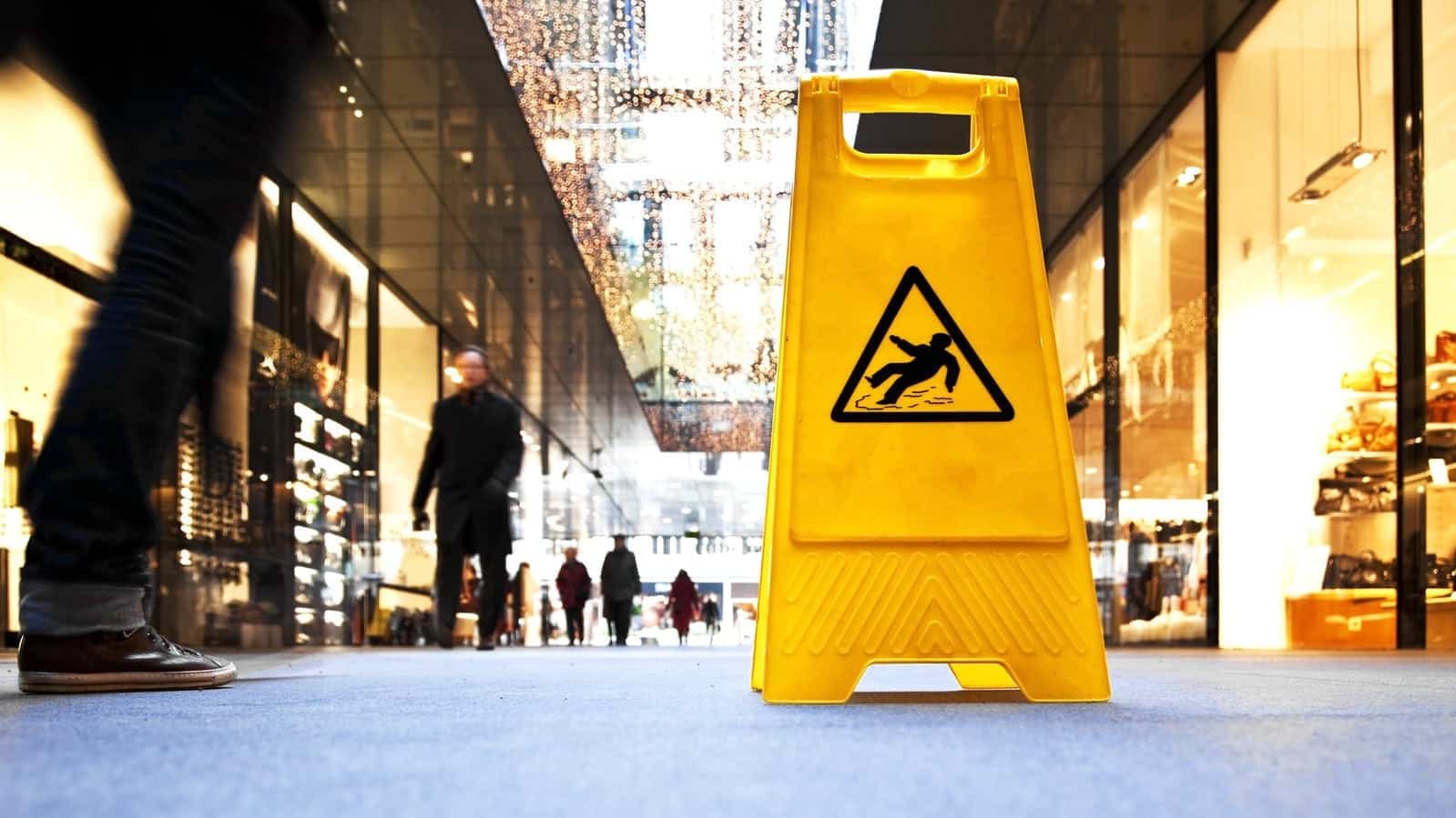Danger sign in a shopping mall, in the background are motion blurred people.
