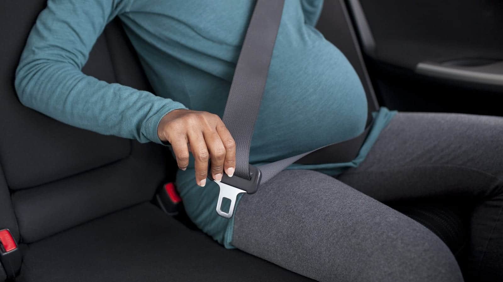 Pregnant woman putting safety belt.