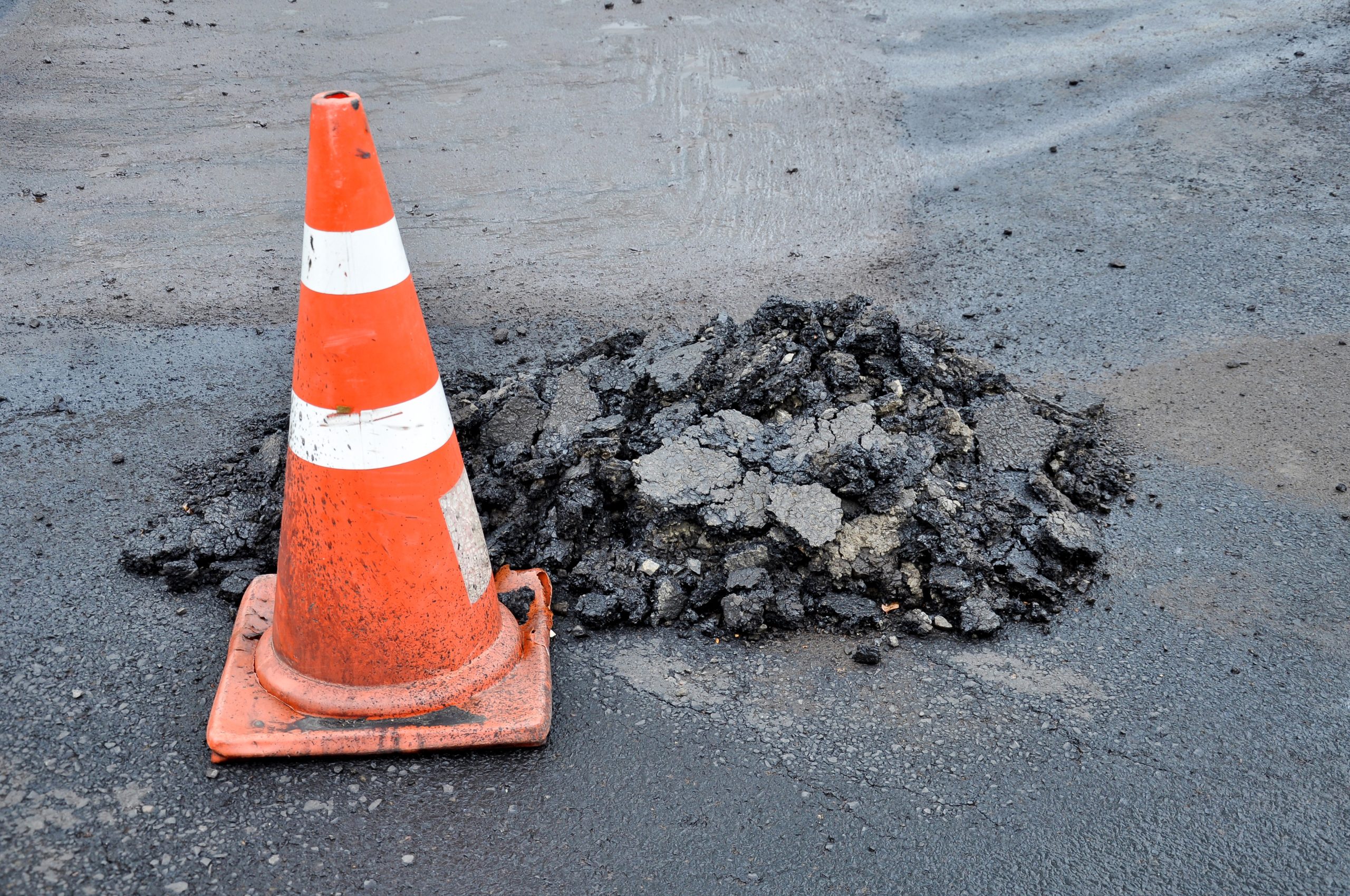 Traffic cones and mounds of asphalt, while road repairs.