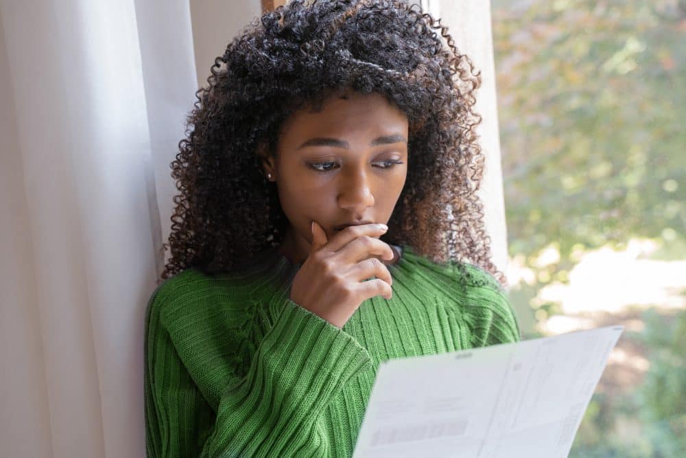 A young woman feeling stressed looking at her bills after a personal injury accident.